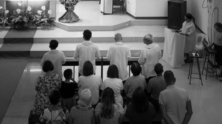 A solemn black and white photo of a church service in Quezon City, Philippines, capturing the spiritual ambiance and community worship.